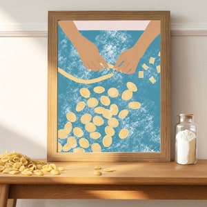 K&ouml;nnte beinhalten: Eine gerahmte Illustration von zwei H&auml;nden, die auf einer blauen Oberfl&auml;che mit wei&szlig;em Mehl Pasta herstellen. Die H&auml;nde formen eine lange Pasta-Str&auml;hne, und es sind viele kleine, runde Pastast&uuml;cke um sie herum verstreut.
