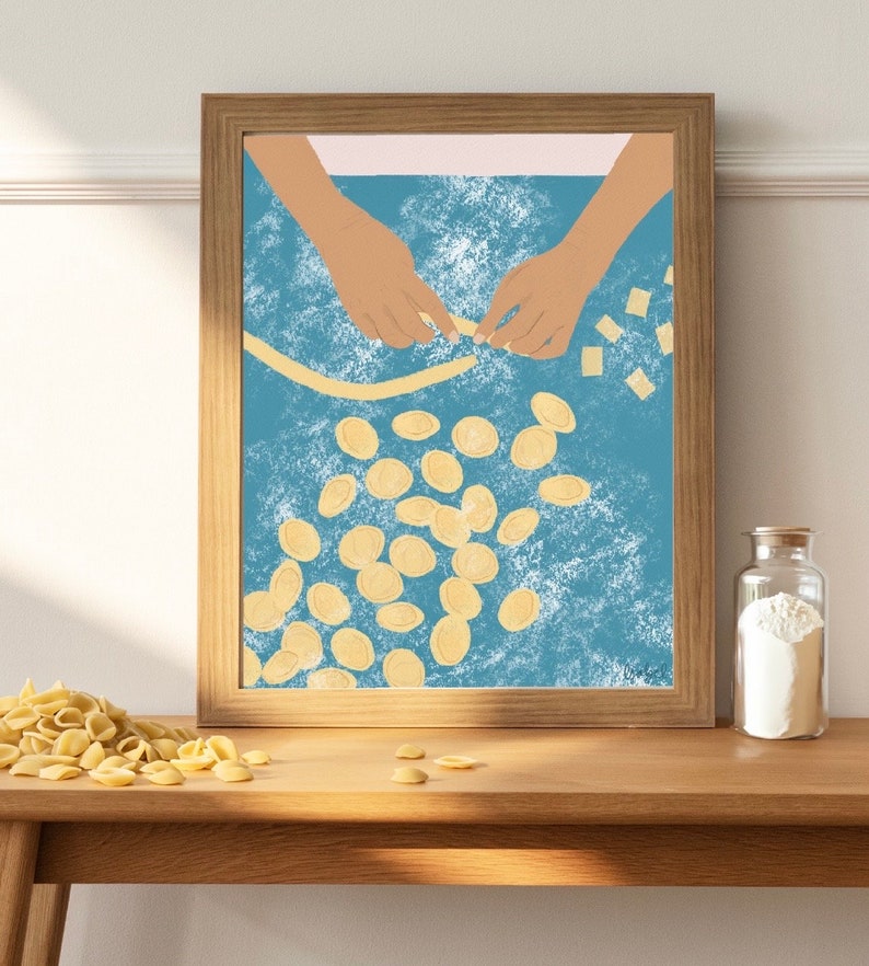 K&ouml;nnte beinhalten: Eine gerahmte Illustration von zwei H&auml;nden, die auf einer blauen Oberfl&auml;che mit wei&szlig;em Mehl Pasta herstellen. Die H&auml;nde formen eine lange Pasta-Str&auml;hne, und es sind viele kleine, runde Pastast&uuml;cke um sie herum verstreut.