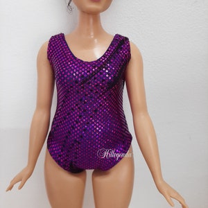 May include: A purple swimsuit with a sparkly, dotted pattern. The swimsuit has a scoop neck and sleeveless design.