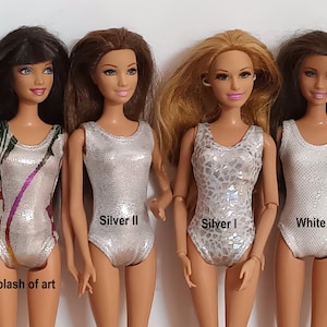 May include: Four Barbie dolls wearing different leotards. The leotards are silver with different patterns and one is white. The dolls are standing in a row and the leotards are labeled "Splash of art", "Silver II", "Silver I", and "White".