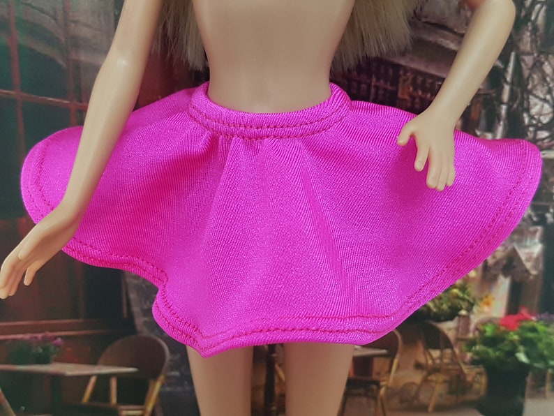 May include: A bright pink mini skirt with a ruffled hem and a simple design. The skirt is made of a soft, stretchy fabric.
