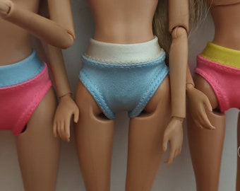 May include: Three pairs of doll underwear in pink, blue, and yellow. Each pair has a contrasting colored band at the top.