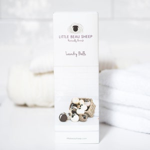 Puede incluir: Una caja blanca con un logotipo de oveja marr&oacute;n y el texto "Little Beau Sheep Naturally British Laundry Balls" y el sitio web "littlebeausheep.com". La caja muestra una cesta de bolas de lavado marrones y blancas.