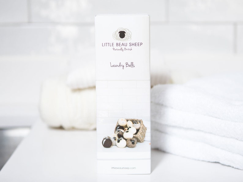 Puede incluir: Una caja blanca con un logotipo de oveja marr&oacute;n y el texto "Little Beau Sheep Naturally British Laundry Balls" y el sitio web "littlebeausheep.com". La caja muestra una cesta de bolas de lavado marrones y blancas.