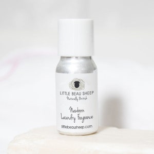 May include: A small, silver-colored bottle with a white cap. The label reads "LITTLE BEAU SHEEP Naturally British" and "Newborn Laundry Fragrance". The bottle is designed for laundry use and has a clean, minimalist aesthetic.