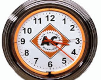 Puede incluir: Un reloj de neón de estilo vintage con un anillo de neón naranja alrededor del borde. La esfera del reloj es blanca con números negros y un logotipo negro y naranja para Allis-Chalmers Manufacturing Company en Milwaukee.