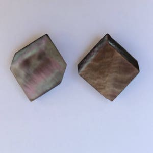 Puede incluir: Dos pendientes de forma cuadrada con un corte de diamante. Un pendiente es de color marrón oscuro con un patrón de mármol. El otro pendiente es de color marrón claro con un patrón de mármol con toques de rosa y verde.