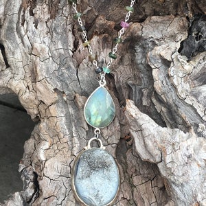 May include: A silver chain necklace with a green and gray teardrop-shaped pendant and a round, gray and white agate pendant.