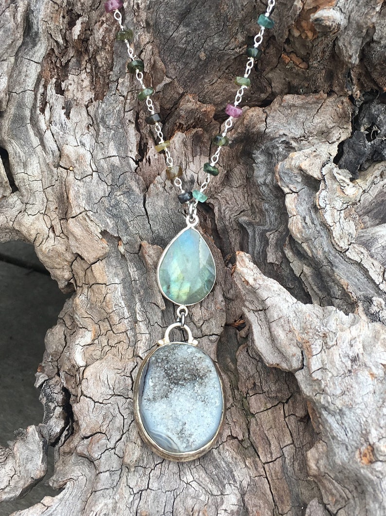 May include: A silver chain necklace with a green and gray teardrop-shaped pendant and a round, gray and white agate pendant.