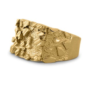 May include: A gold ring with a textured, nugget-like design. The ring is wide and has a flat top.