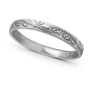 Può includere: Un anello a fascia d'argento con un design inciso intricato. L'anello è sottile e delicato, con una finitura liscia.