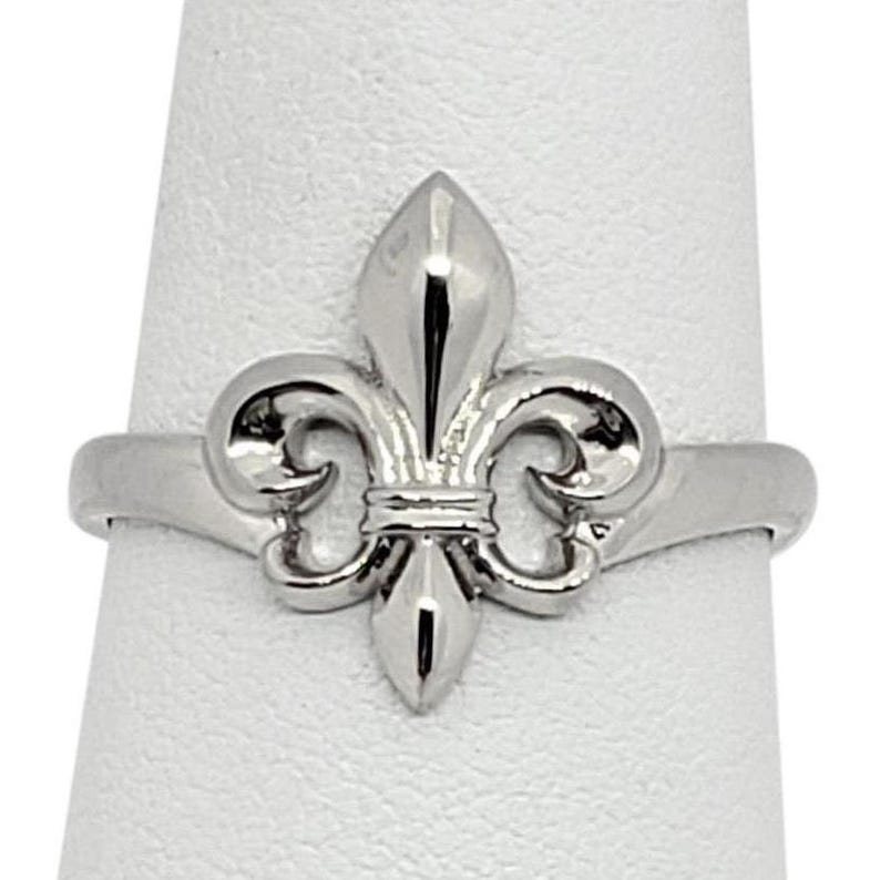A silver ring with a fleur-de-lis design on it.