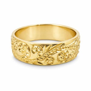 May include: A polished yellow gold band ring featuring an intricate, continuous engraved pattern of stylized floral motifs and swirling leaves that wrap around the entire outer surface of the metal band with a bright, reflective finish.
