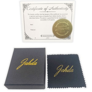 May include: A black box with the word "Jahda" in gold lettering. The box is next to a black polishing cloth with the same gold lettering. A certificate of authenticity with a gold seal that reads "Certified Authentic Gold Official Seal" is also included.