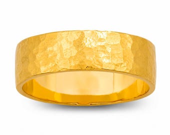 May include: A wide, gold-colored ring with a hammered texture. The ring has a smooth interior and a textured exterior, creating a unique visual appeal. The ring is a solid band, showcasing a bright, polished finish.
