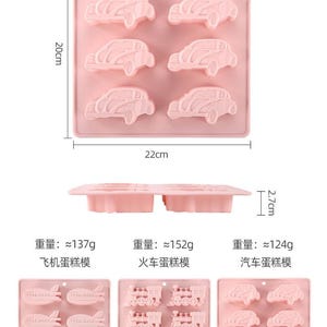 May include: Pink silicone baking molds for making airplane, train, and car shaped cakes. The molds are 22 cm wide and 2.7 cm tall. The molds are labeled with the weight of the finished cake in grams.