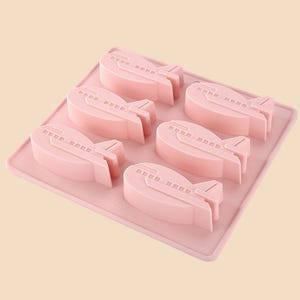 May include: Pink silicone mold with six airplane-shaped cavities. The mold is designed for making chocolate or candy.