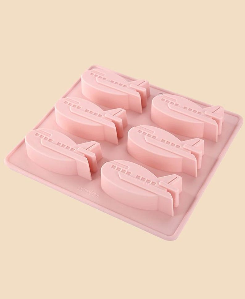 May include: Pink silicone mold with six airplane-shaped cavities. The mold is designed for making chocolate or candy.