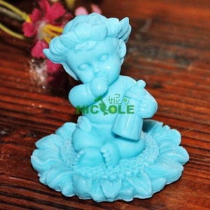 Könnte beinhalten: Eine hellblaue Baby-Cherub-Figur, die eine Flasche hält und auf einer hellblauen Sonnenblume sitzt.