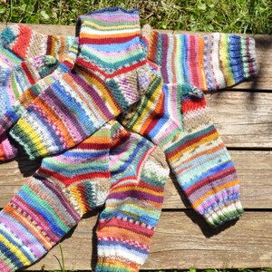 May include: A set of four colorful striped socks made of knitted wool. The socks are in various shades of red, blue, green, yellow, and white.