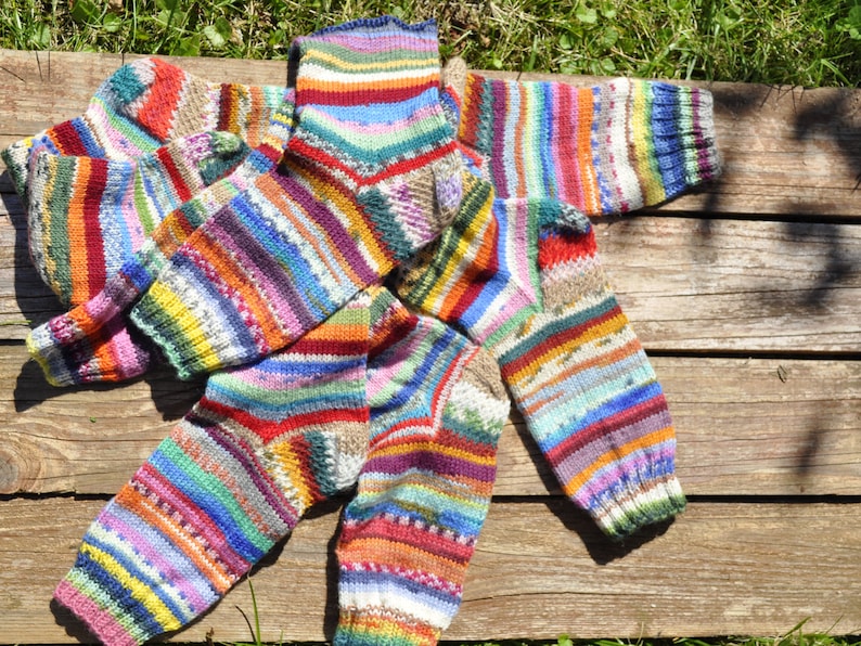 May include: A set of four colorful striped socks made of knitted wool. The socks are in various shades of red, blue, green, yellow, and white.