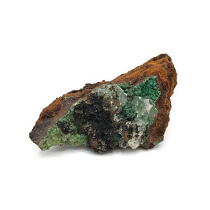 May include: A rough, brown rock with green and white mineral deposits. The rock has a natural, earthy texture.