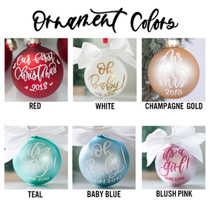 May include: Six different colored Christmas ornaments with white ribbon bows. The ornaments are red, white, champagne gold, teal, baby blue, and blush pink. Each ornament has a different inscription on it. The inscriptions are "Our first Christmas 2018", "Oh Baby! Apr 2019", "Mr. & Mrs. 2018", "It's a Boy! June 2019", "Oh Baby! May 2019", and "It's a Girl! Mar 2019".