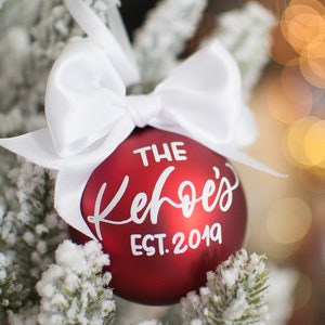 May include: Red Christmas ornament with a white bow and the text "THE Kehoe's EST. 2019" on it.
