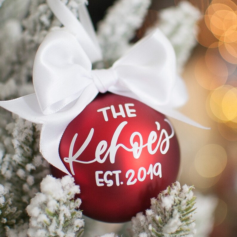 May include: Red Christmas ornament with a white bow and the text "THE Kehoe's EST. 2019" on it.