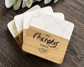May include: Set of four wooden coasters with a marble design and the text "The Murphy Family" in a cursive font. The coasters have a natural wood finish and a white marble top.