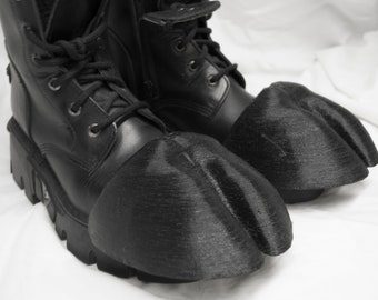 May include: A pair of black leather boots with attached black hoof-shaped covers. The boots have laces and thick soles. The hoof covers are textured and appear to be made of a rigid material, creating a unique, fantasy-themed footwear.
