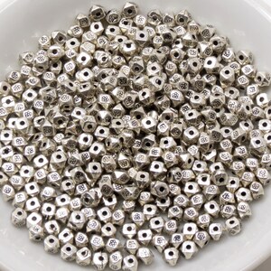 May include: A large pile of silver metal beads with a pyramid shape and a textured surface.