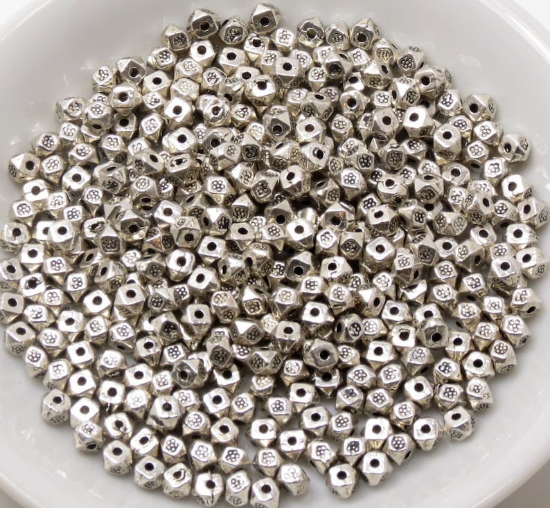 May include: A large pile of silver metal beads with a pyramid shape and a textured surface.