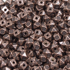 K&ouml;nnte beinhalten: Ein gro&szlig;er Haufen kupferfarbener Metallperlen. Jede Perle hat eine Pyramidenform mit einem Loch in der Mitte. Die Perlen haben eine strukturierte Oberfl&auml;che.