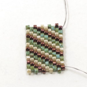 May include: A small square of beadwork with a geometric pattern. The beads are in shades of brown, green, and cream.