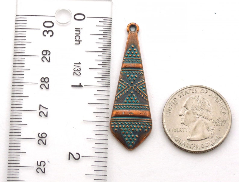 May include: A copper-colored pendant with a turquoise and copper geometric design. The pendant is about 1 inch long and is shown next to a US quarter for size comparison.