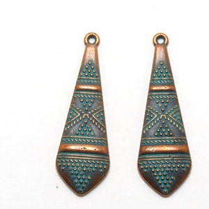 May include: Two copper-colored pendant charms with a teal blue geometric design. The charms are shaped like a teardrop and have a small loop at the top for attaching to jewelry.