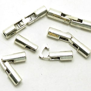 May include: Silver-toned metal jewelry clasps in various configurations. The clasps are rectangular with a hinged design, some connected and others separate. The metal has a shiny, reflective surface. The clasps are likely for necklaces or bracelets.