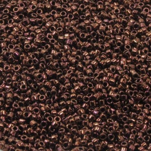 May include: A close-up view of a large quantity of small, round, dark brown seed beads. The beads have a metallic sheen and are scattered randomly.