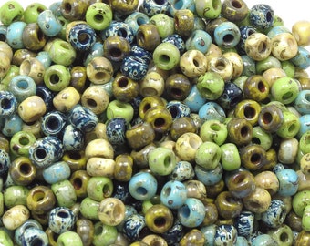 May include: A large pile of colorful ceramic beads in shades of blue, green, brown, and cream. The beads are small and round with a hole in the center. They are perfect for jewelry making or other craft projects.