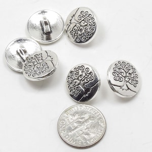 May include: Six silver-toned buttons with a tree of life design. The buttons are approximately the size of a US dime.