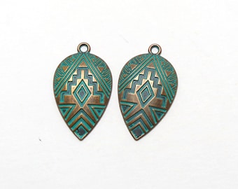 May include: Two teal and bronze colored metal pendant charms with a geometric design. The charms are shaped like teardrops and have a hole at the top for hanging.
