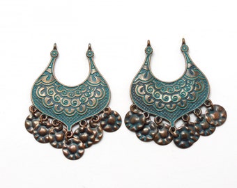 May include: A pair of ornate, copper-toned earrings with a turquoise blue enamel finish. Each earring features a crescent-shaped design with intricate details and a dangling row of round, textured discs.