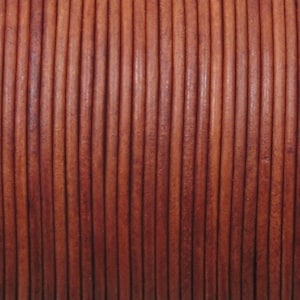 May include: Close-up of a spool of brown leather cord. The cord is tightly wound, with each strand appearing as a vertical line. The color varies from light to dark brown, creating a textured appearance. This leather cord is suitable for jewelry making and crafting.