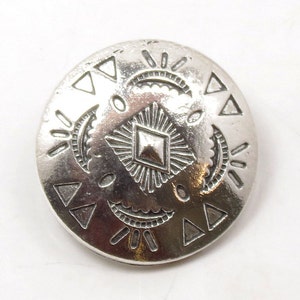May include: Silver button with a geometric design featuring triangles, diamonds, and sunburst patterns.