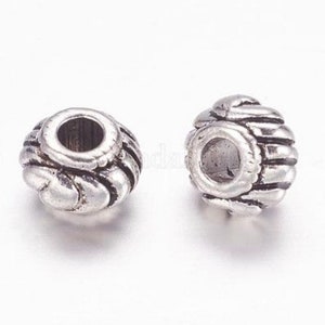 Op de afbeelding: Twee zilveren metalen kralencaps met een decoratief, getextureerd ontwerp. De kralencaps zijn rond van vorm met een gat in het midden.