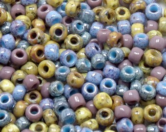 May include: A close-up of a collection of small, round, ceramic beads in shades of brown, blue, and purple. The beads have a speckled, textured finish.