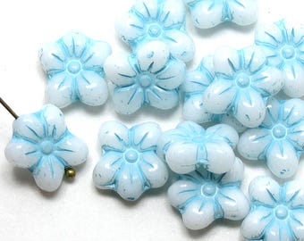 May include: A collection of light blue glass flower beads with a white opaque center. The beads have a raised flower design and are perfect for jewelry making.