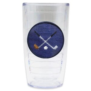 May include: A clear plastic tumbler with a blue and white embroidered patch featuring crossed golf clubs and a golf ball.
