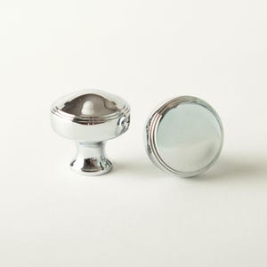 May include: Two polished chrome cabinet knobs. The knobs have a rounded top and a decorative base. The image shows the knobs against a white background. The knobs are sold as a 2-pack.